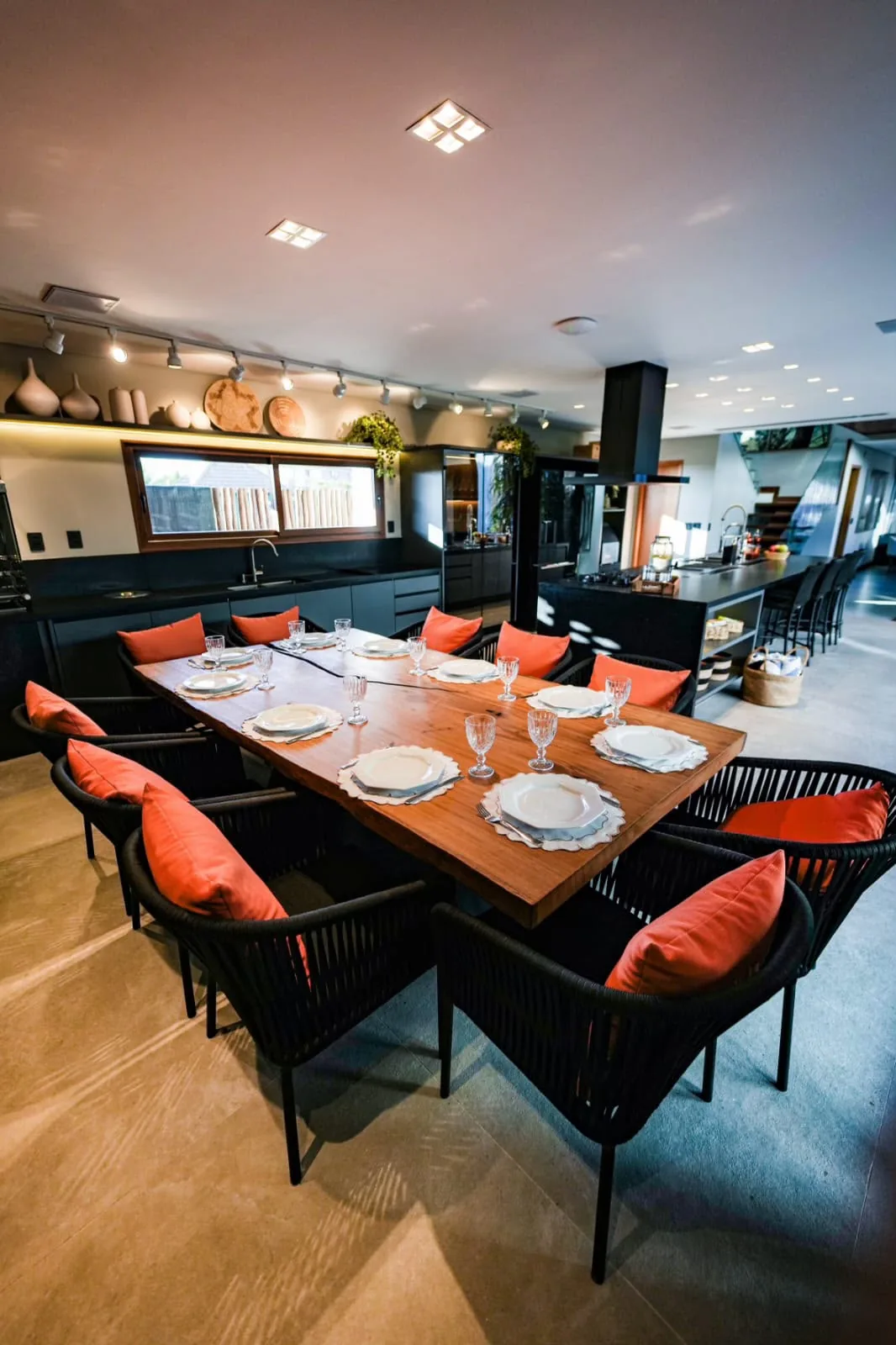 Sala de jantar com mesa ampla e cadeiras de fibra, sob pendentes