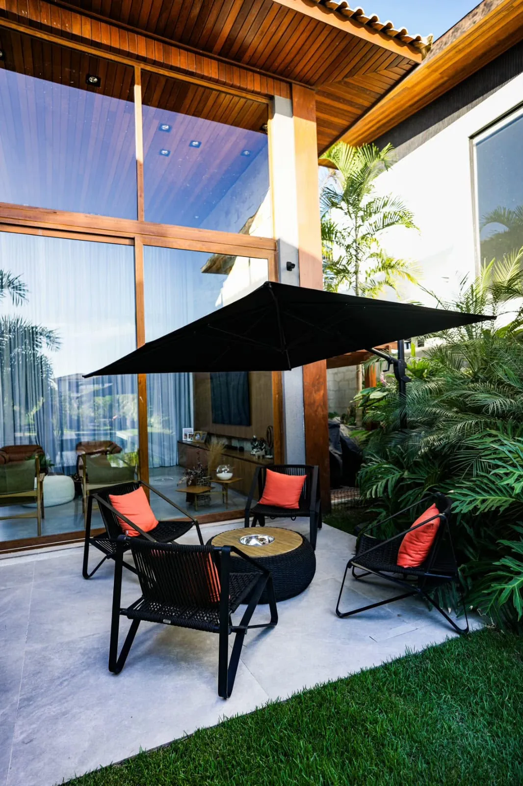 Terraço coberto com guarda-sol e poltronas, de frente para o jardim