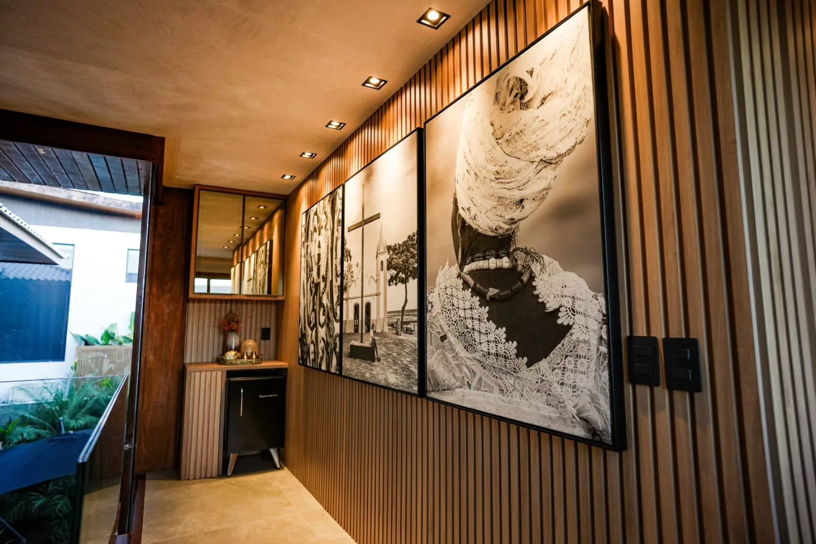 Hall com painel artístico emoldurado e acesso à escada de madeira