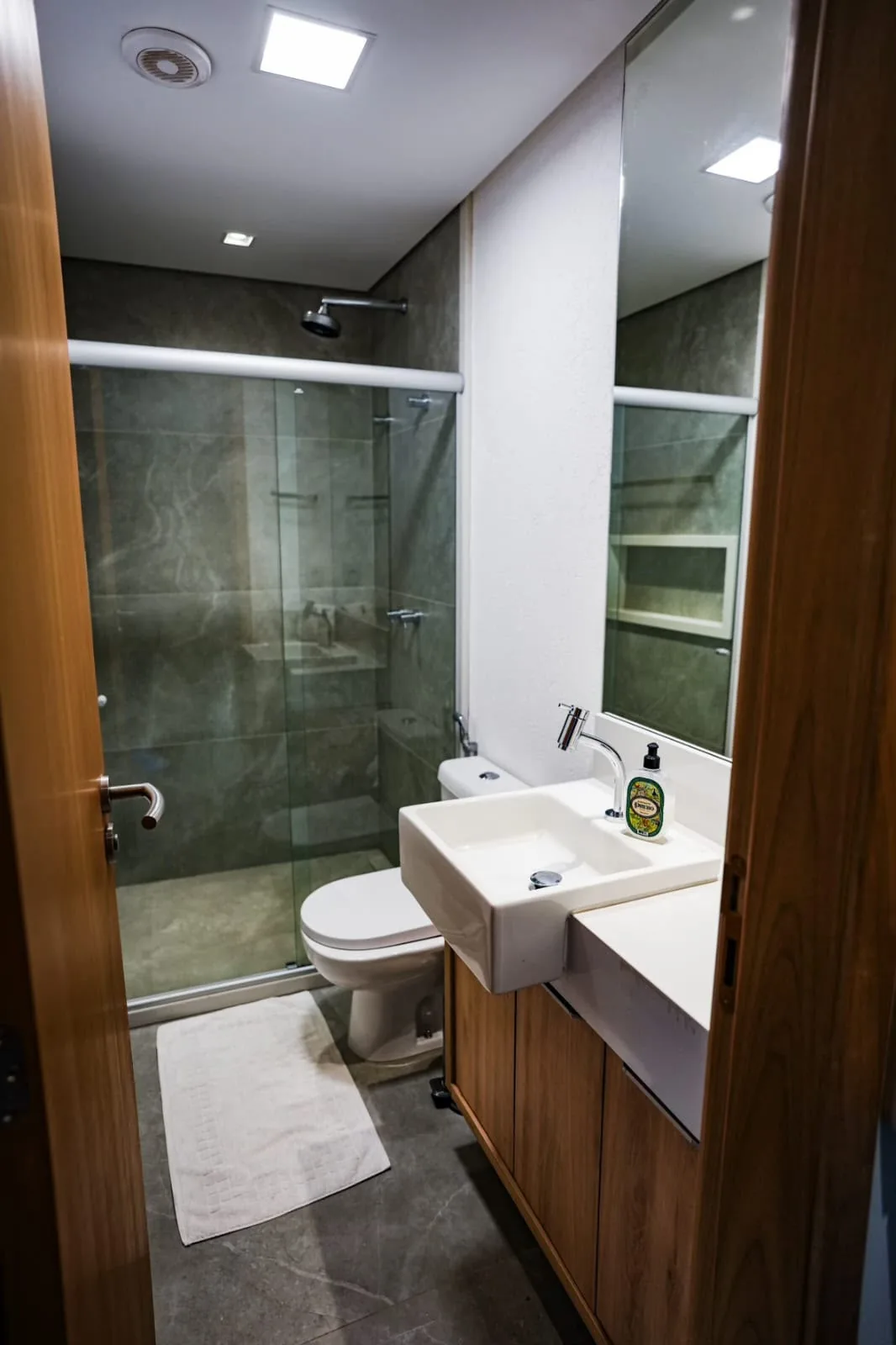 Banheiro com box de vidro, ducha e acabamento contemporâneo