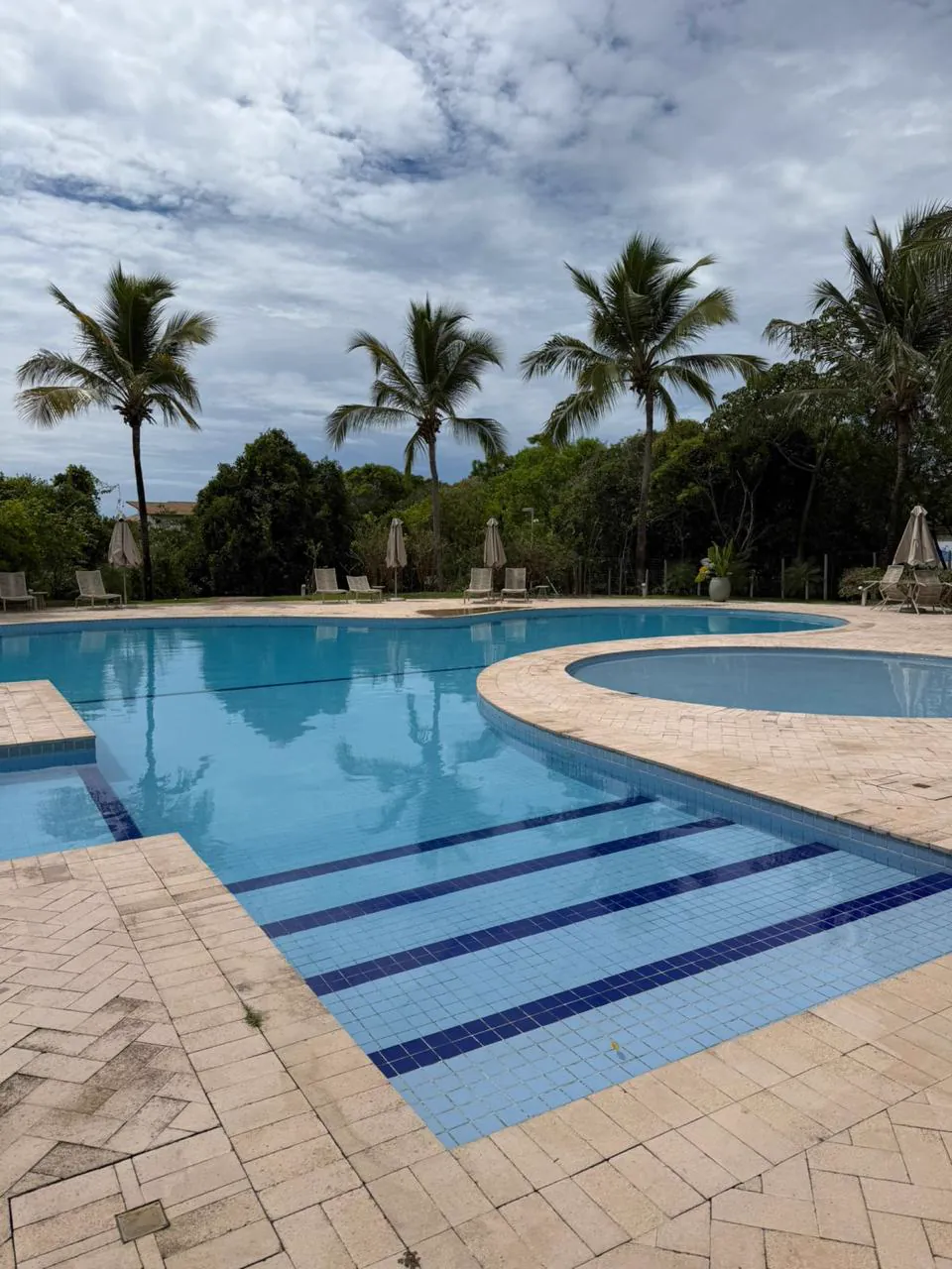 Piscina do condomínio com prainha e coqueiros